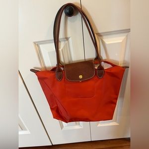 Medium size orange Longchamp purse.